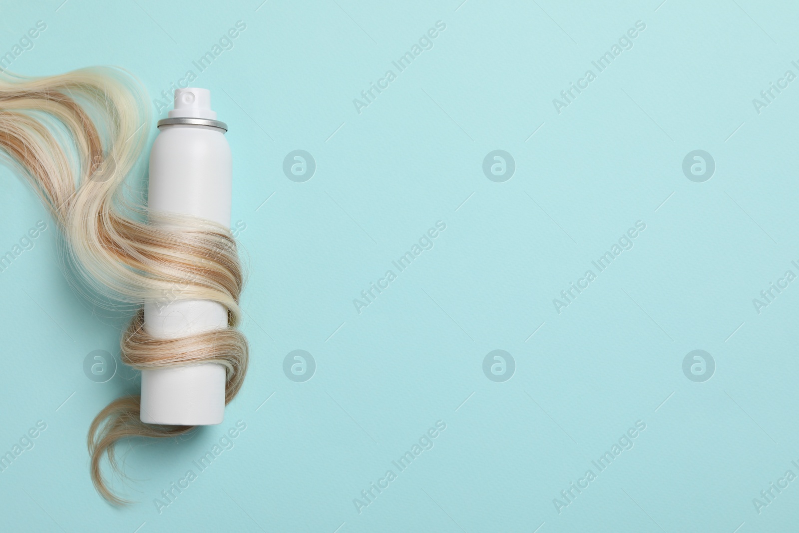 Photo of Lock of healthy blond hair and cosmetic product on turquoise background, flat lay. Space for text