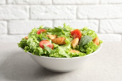 Delicious salad with chicken and cherry tomato on light grey table, closeup