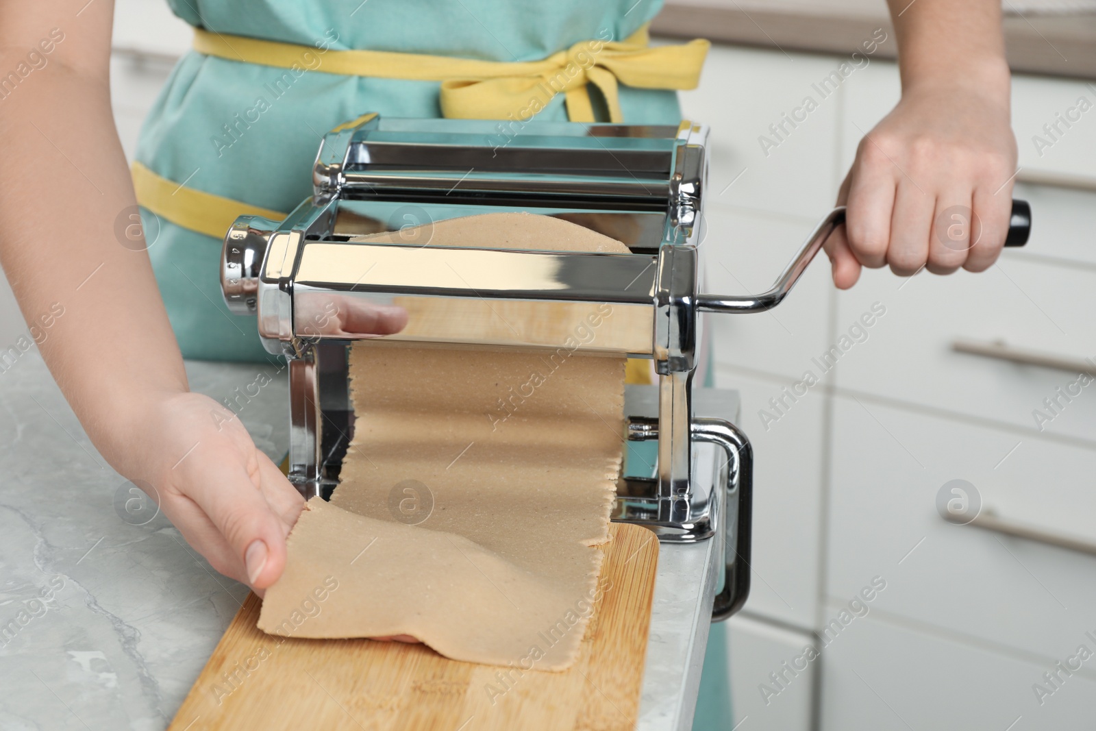 Photo of Woman making dough for soba (buckwheat noodles) at light grey marble table indoors, closeup