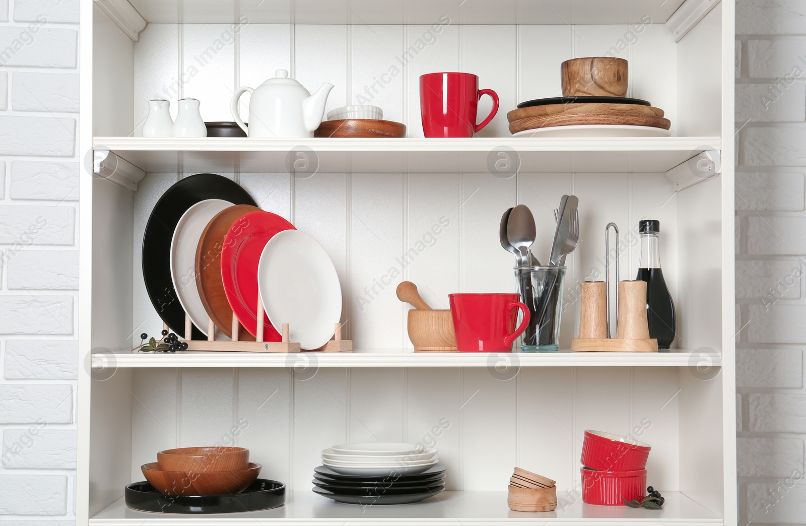 Photo of White shelving unit with set of dishware near brick wall