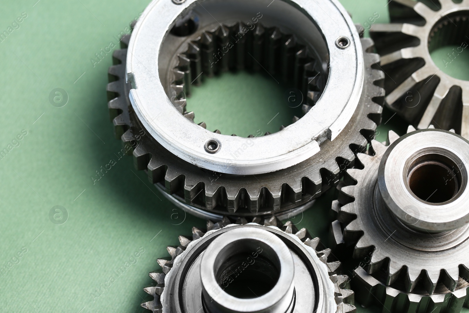 Photo of Different stainless steel gears on light green background, closeup