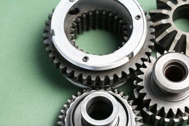 Photo of Different stainless steel gears on light green background, closeup