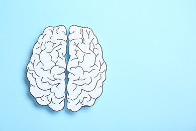Paper brain hemispheres on light blue background, top view. Space for text