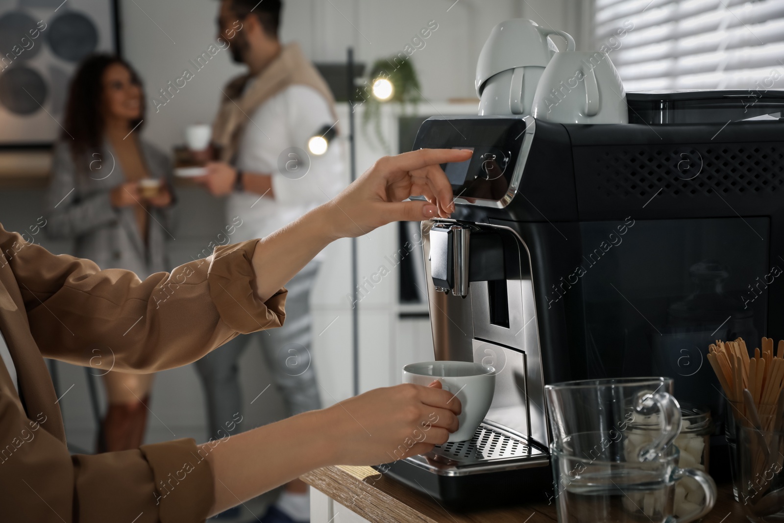 Photo of Woman preparing fresh aromatic coffee with modern machine in office, closeup