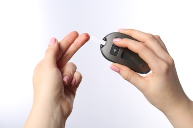 Diabetes. Woman checking blood sugar level with glucometer on white background, closeup