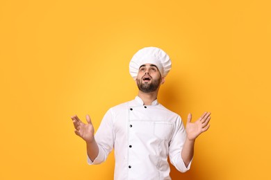 Photo of Surprised chef in uniform on yellow background