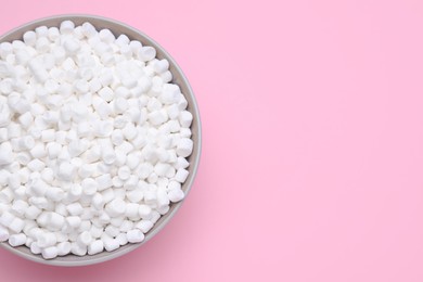Photo of Bowl of sweet marshmallows on pink background, top view. Space for text