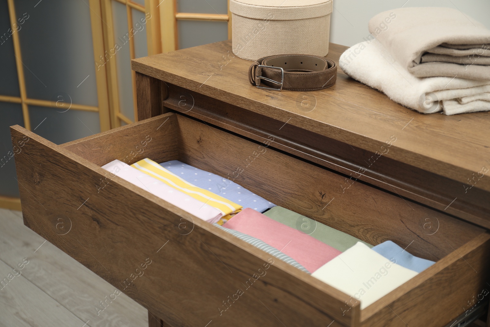 Photo of Chest of drawers with different folded clothes and accessories indoors