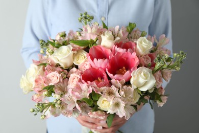 Photo of Woman with beautiful bouquet of fresh flowers on light background, closeup