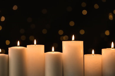 Photo of Burning candles on black background with blurred lights