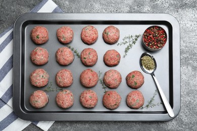 Many fresh raw meatballs on grey table, top view