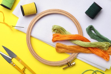 Photo of Flat lay composition with embroidery accessories on yellow background