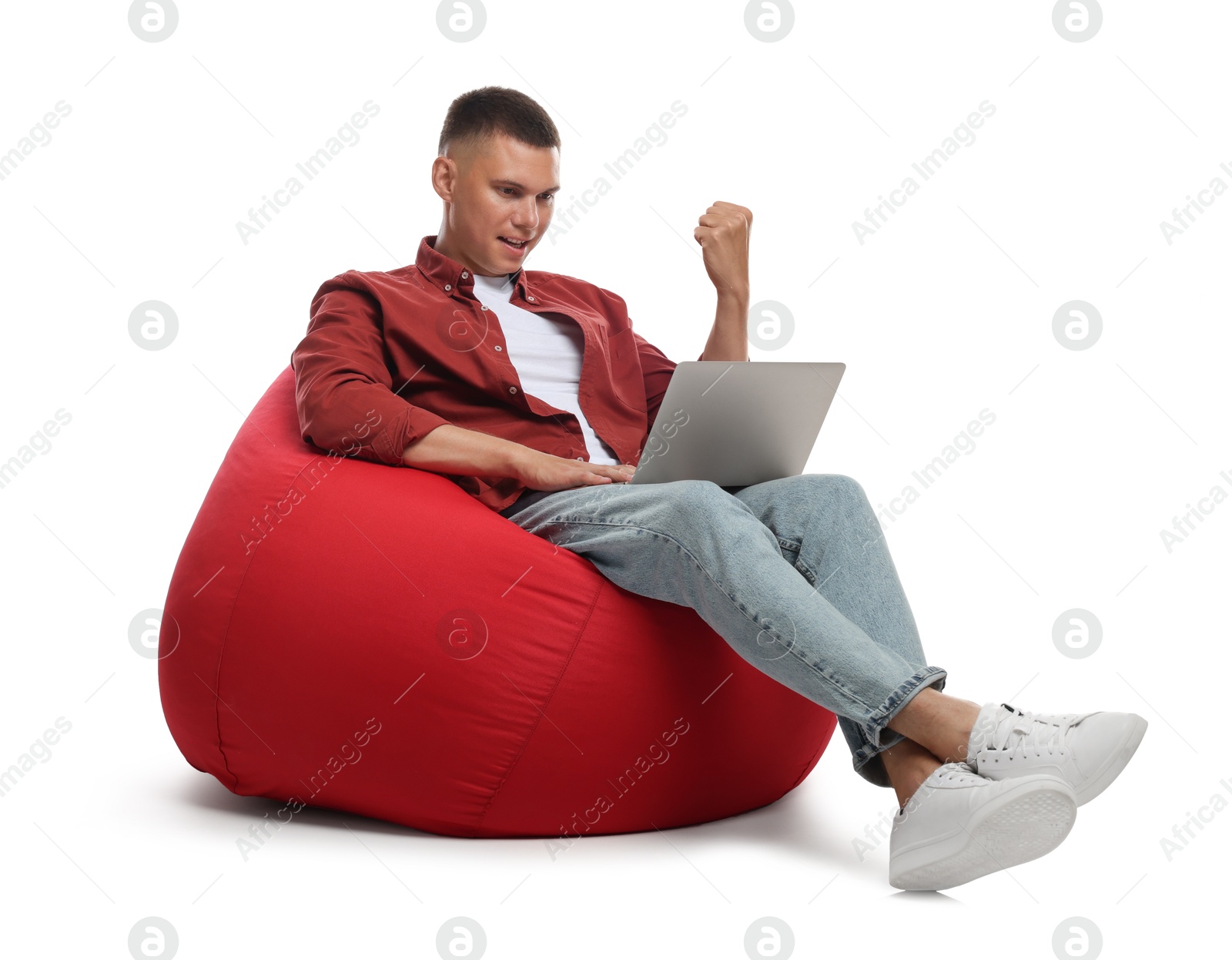 Photo of Man with laptop gesturing on red bean bag chair against white background