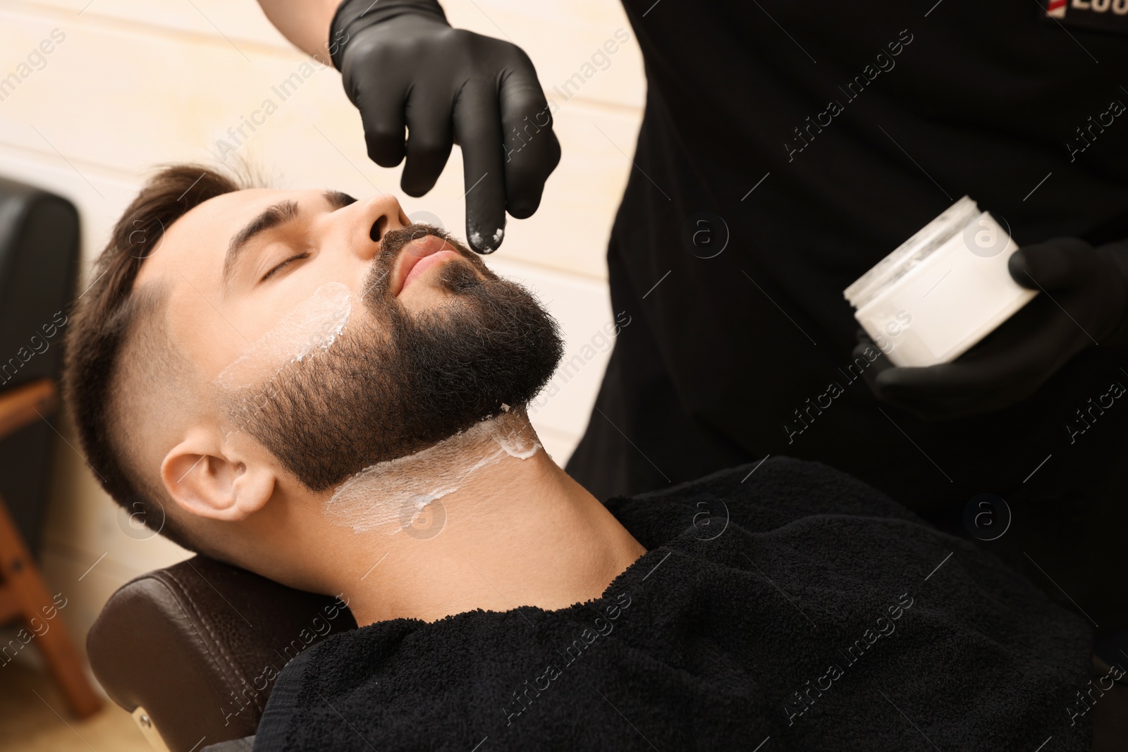 Photo of Professional hairdresser working with client in barbershop, closeup