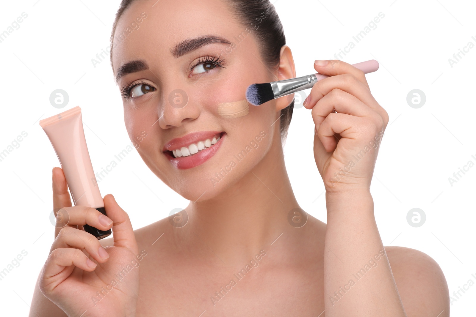 Photo of Woman with tube applying foundation on face using brush against white background