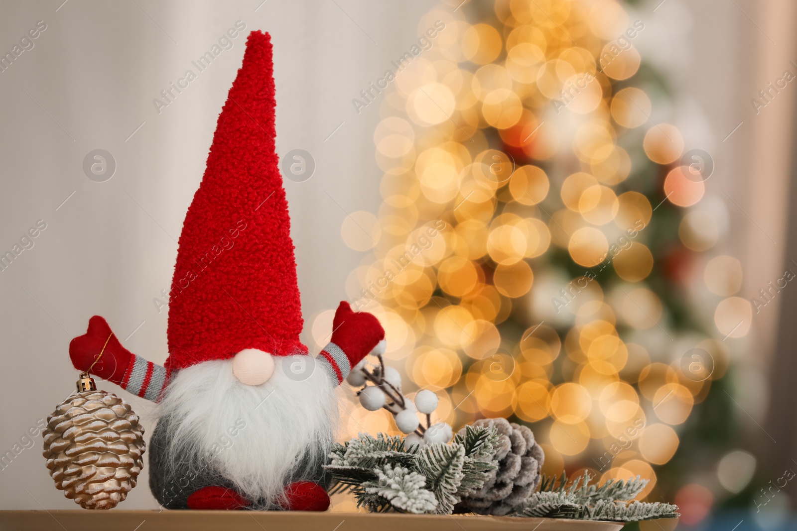 Photo of Cute Christmas gnome on wooden table in decorated room, space for text