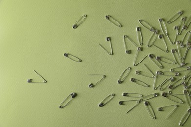 Photo of Many safety pins on green background, flat lay