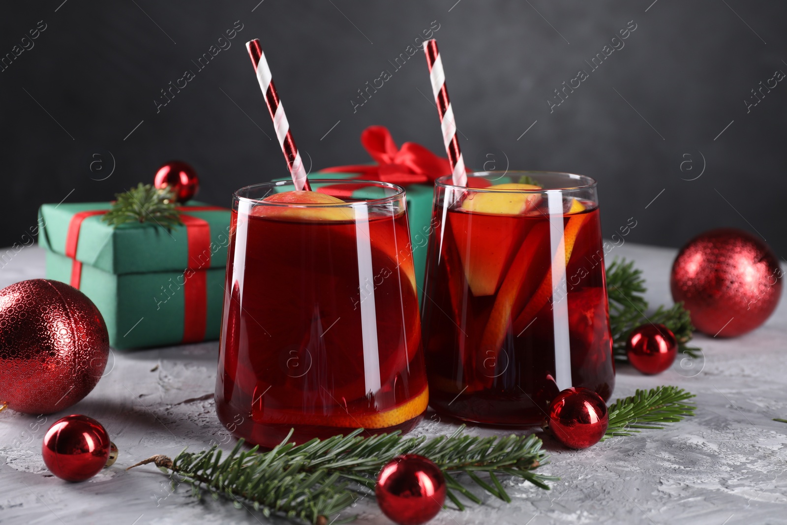 Photo of Delicious Sangria drink in glasses and Christmas decorations on grey textured table, closeup