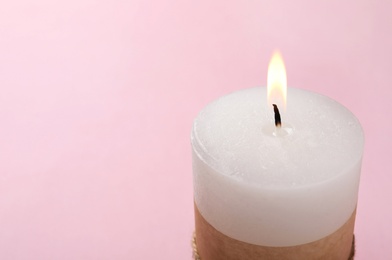 Photo of Burning wax candle on color background, closeup