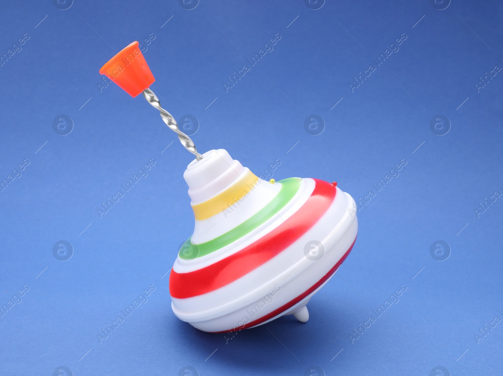 Photo of One bright spinning top on blue background. Toy whirligig