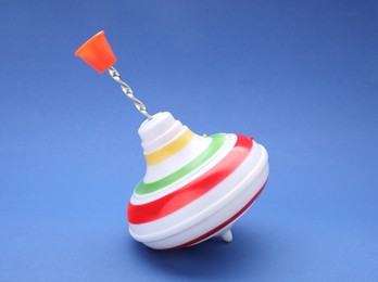 One bright spinning top on blue background. Toy whirligig