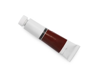 Tube with brown oil paint on white background, top view