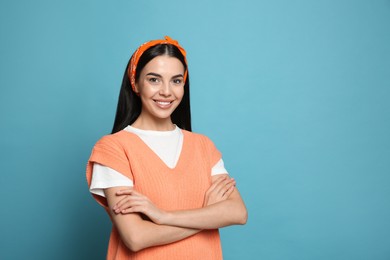 Photo of Young woman wearing stylish bandana on light blue background, space for text