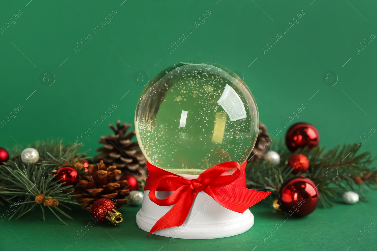 Photo of Beautiful Christmas snow globe and festive decor on green background