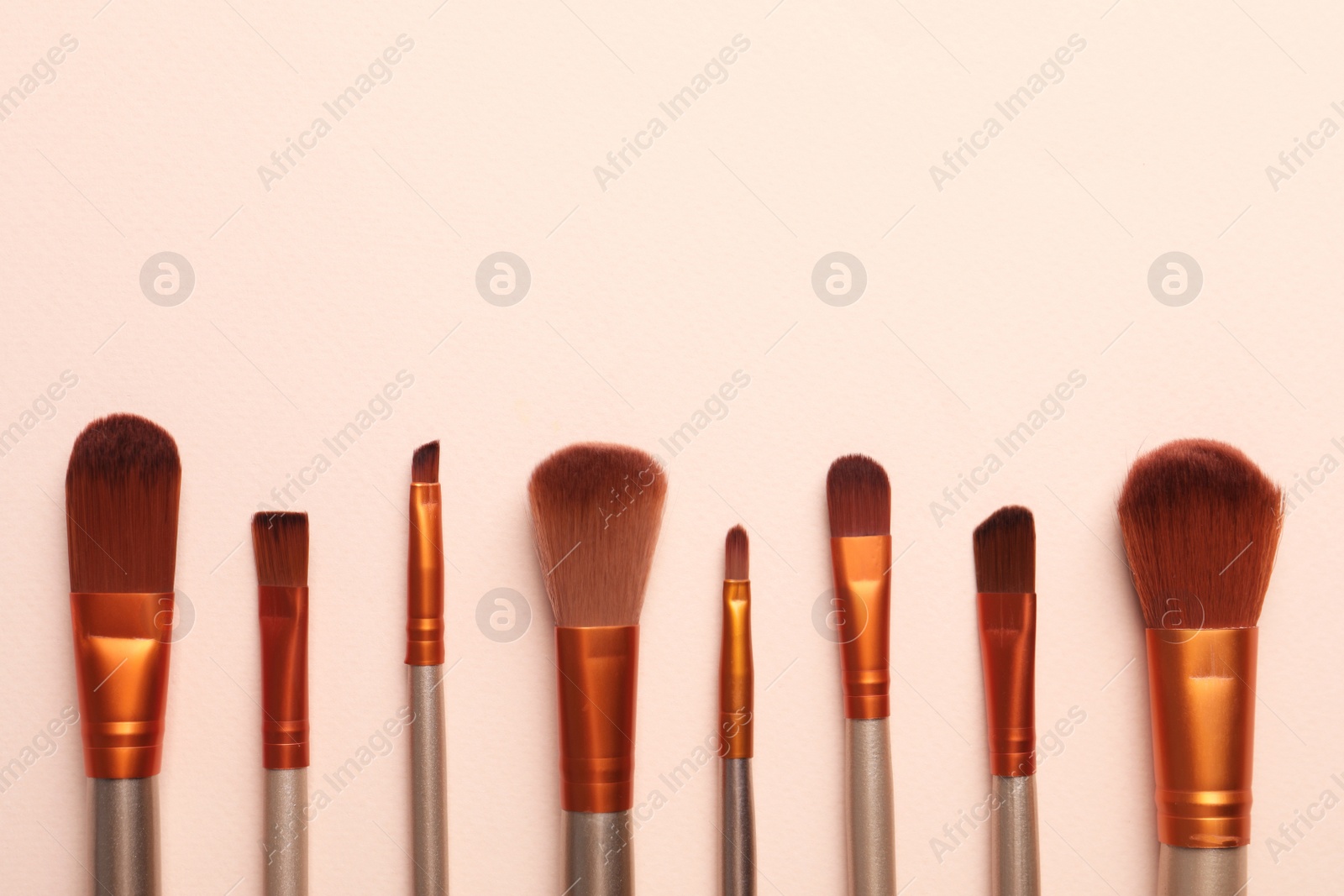 Photo of Set of makeup brushes on beige background, flat lay. Space for text