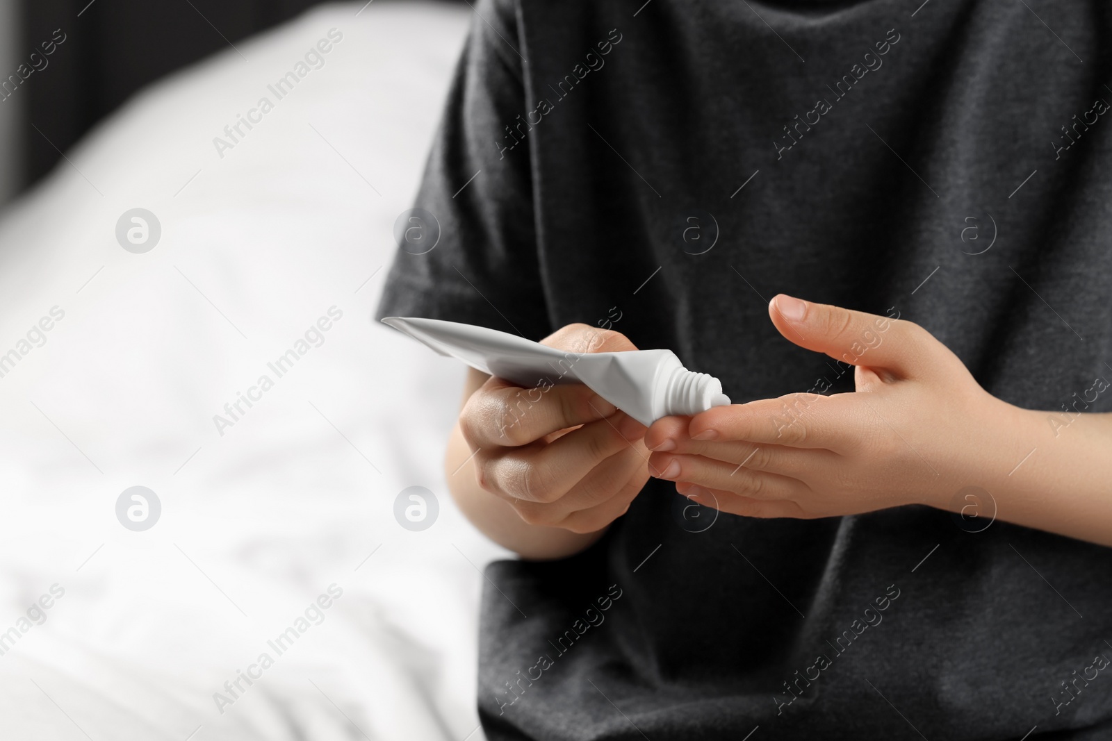 Photo of Child applying ointment onto hand at home, closeup. Space for text