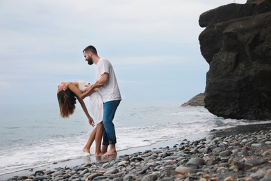 Photo of Happy young couple having fun on beach near sea. Space for text