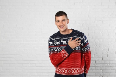 Photo of Portrait of young man in Christmas sweater near white brick wall