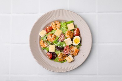 Delicious Caesar salad with shrimps on white tiled table, top view