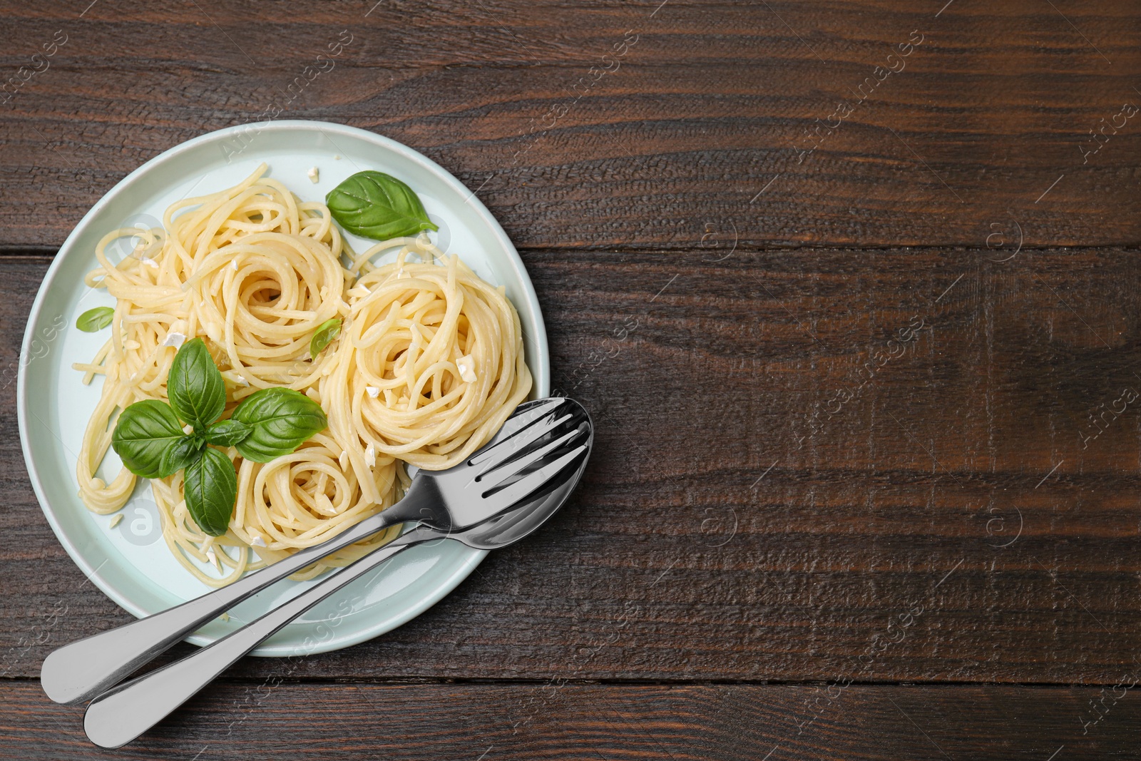 Photo of Delicious pasta with brie cheese and basil leaves on wooden table, top view. Space for text