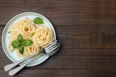 Delicious pasta with brie cheese and basil leaves on wooden table, top view. Space for text