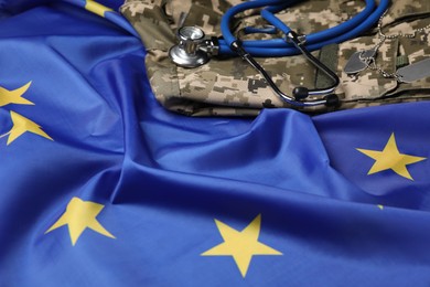 Photo of Stethoscope and military uniform on flag of European Union, closeup