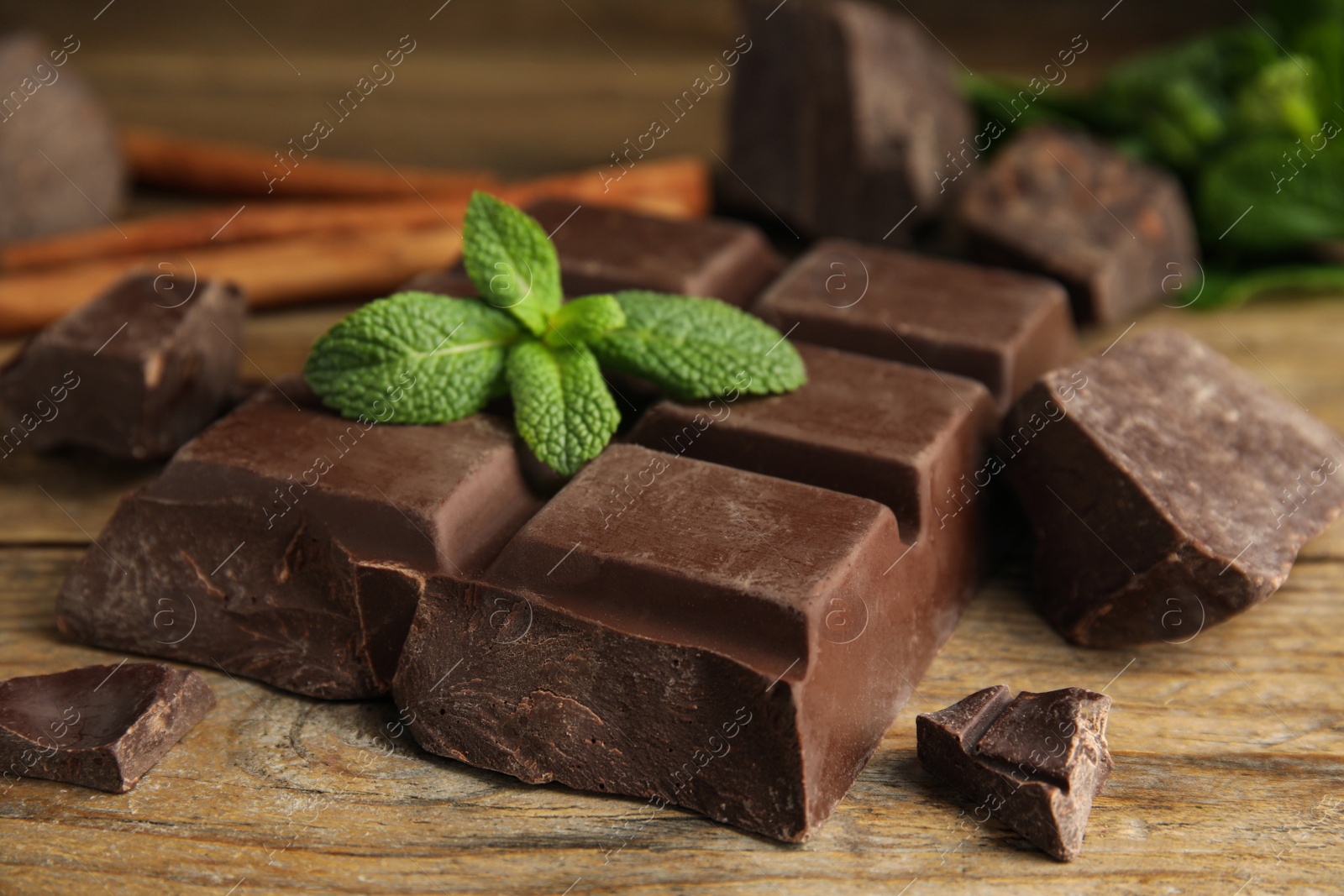 Photo of Tasty chocolate pieces and mint on wooden table, closeup