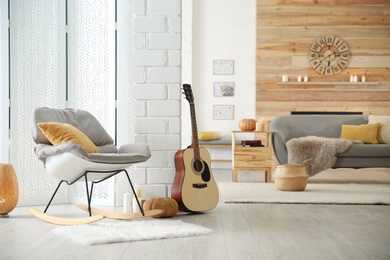 Photo of Cozy living room interior with comfortable furniture, guitar and autumn decor
