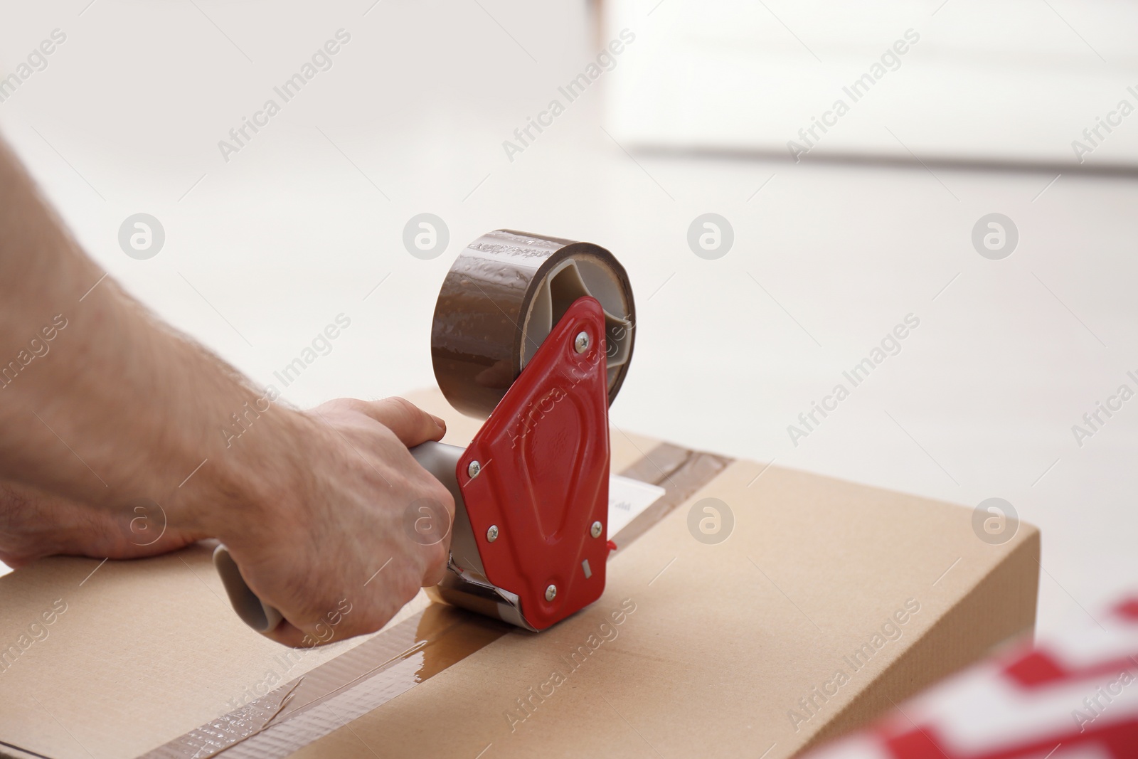 Photo of Man packing carton box indoors, closeup. Moving day