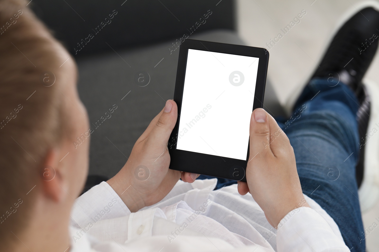 Photo of Man using e-book reader indoors, closeup view