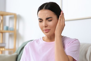 Photo of Young woman suffering from ear pain at home