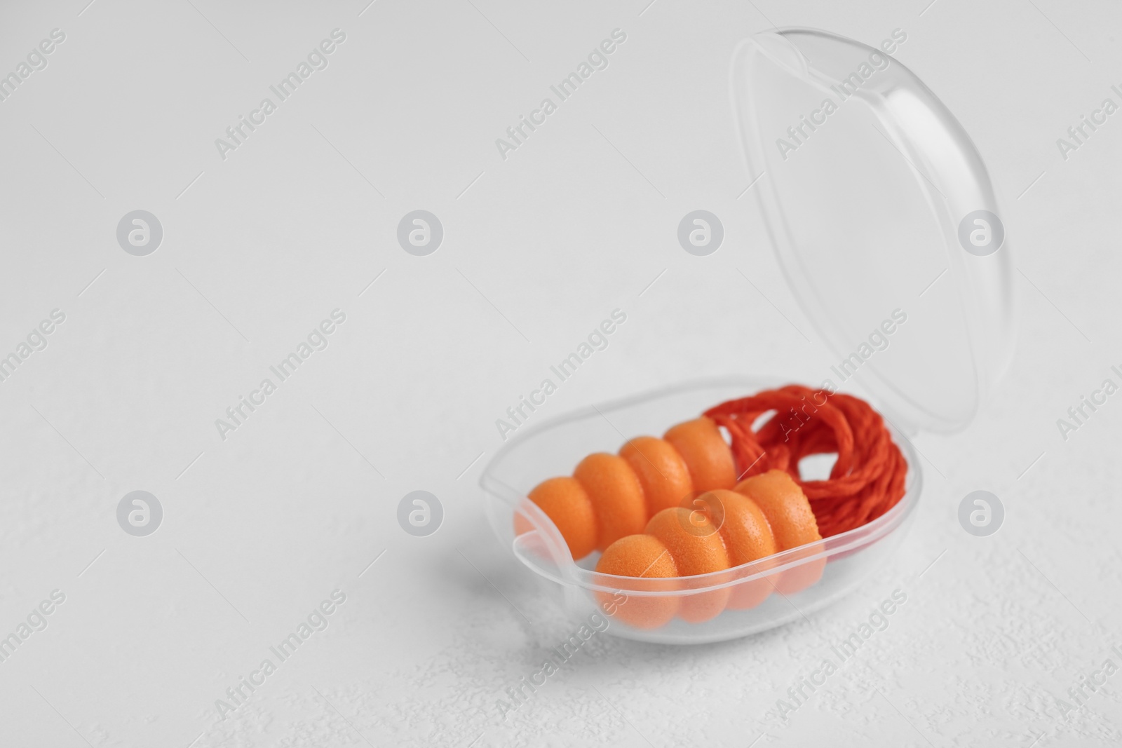 Photo of Pair of orange ear plugs with cord in case on white background. Space for text