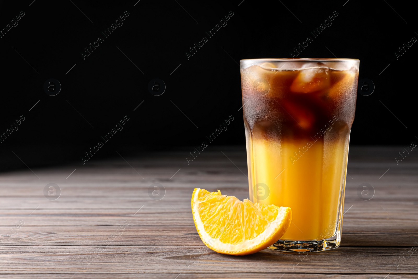 Photo of Tasty refreshing drink with coffee and orange juice on wooden table, space for text