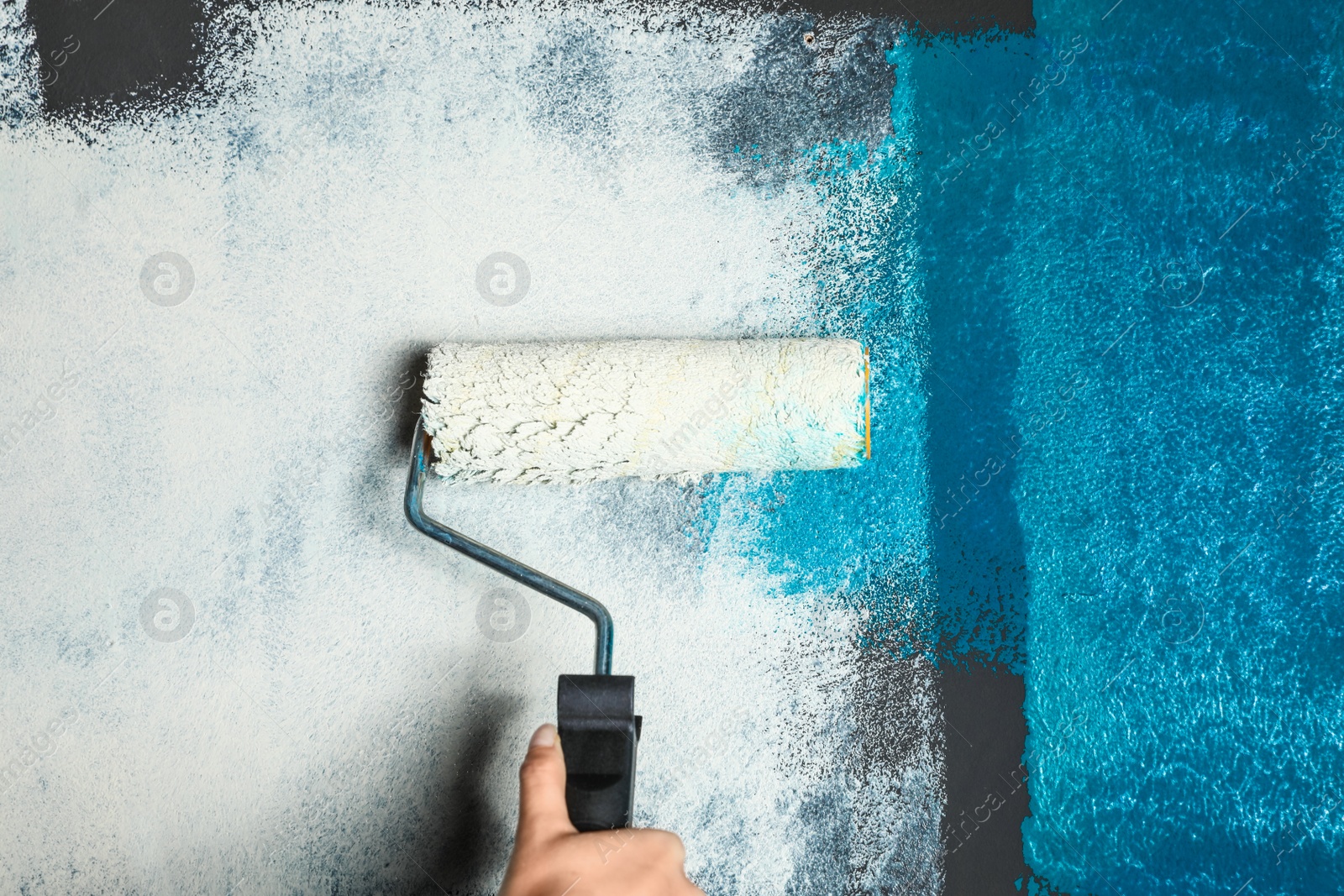 Photo of Woman painting wall with blue dye, closeup