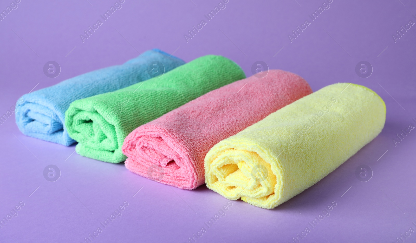 Photo of Many colorful microfiber cloths on light background