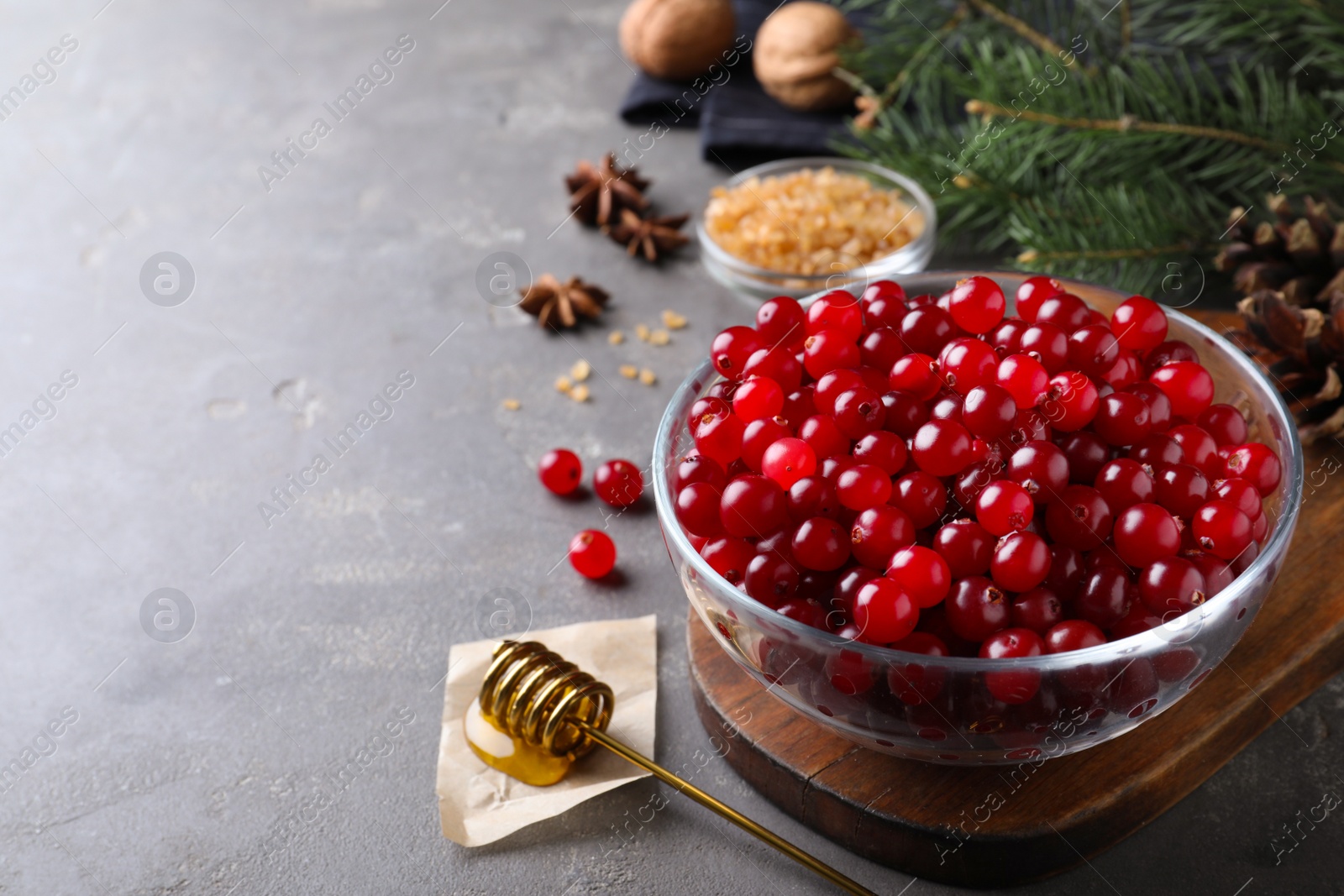 Photo of Fresh ripe cranberries and spices on grey table. Space for text