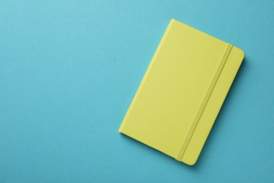 Photo of New stylish planner with hard cover on light blue background, top view. Space for text