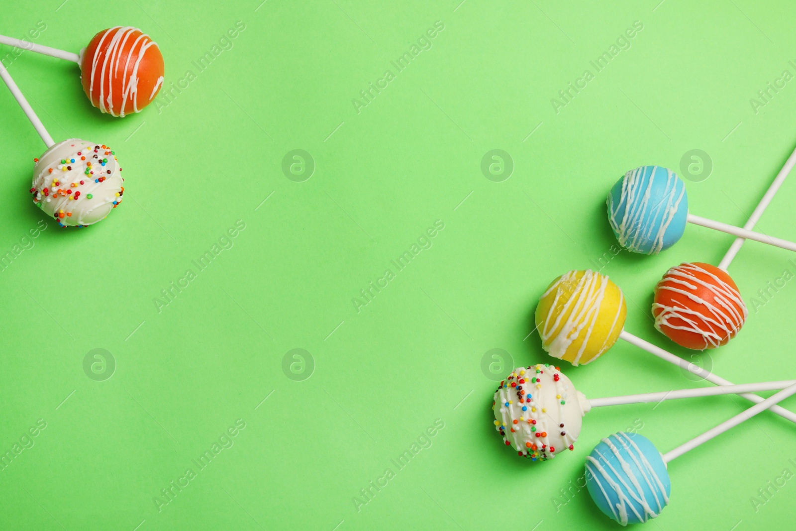 Photo of Bright delicious cake pops on color background, flat lay. Space for text