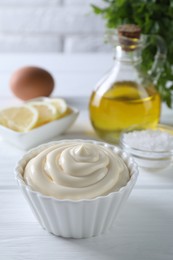 Fresh mayonnaise sauce in bowl on white wooden table