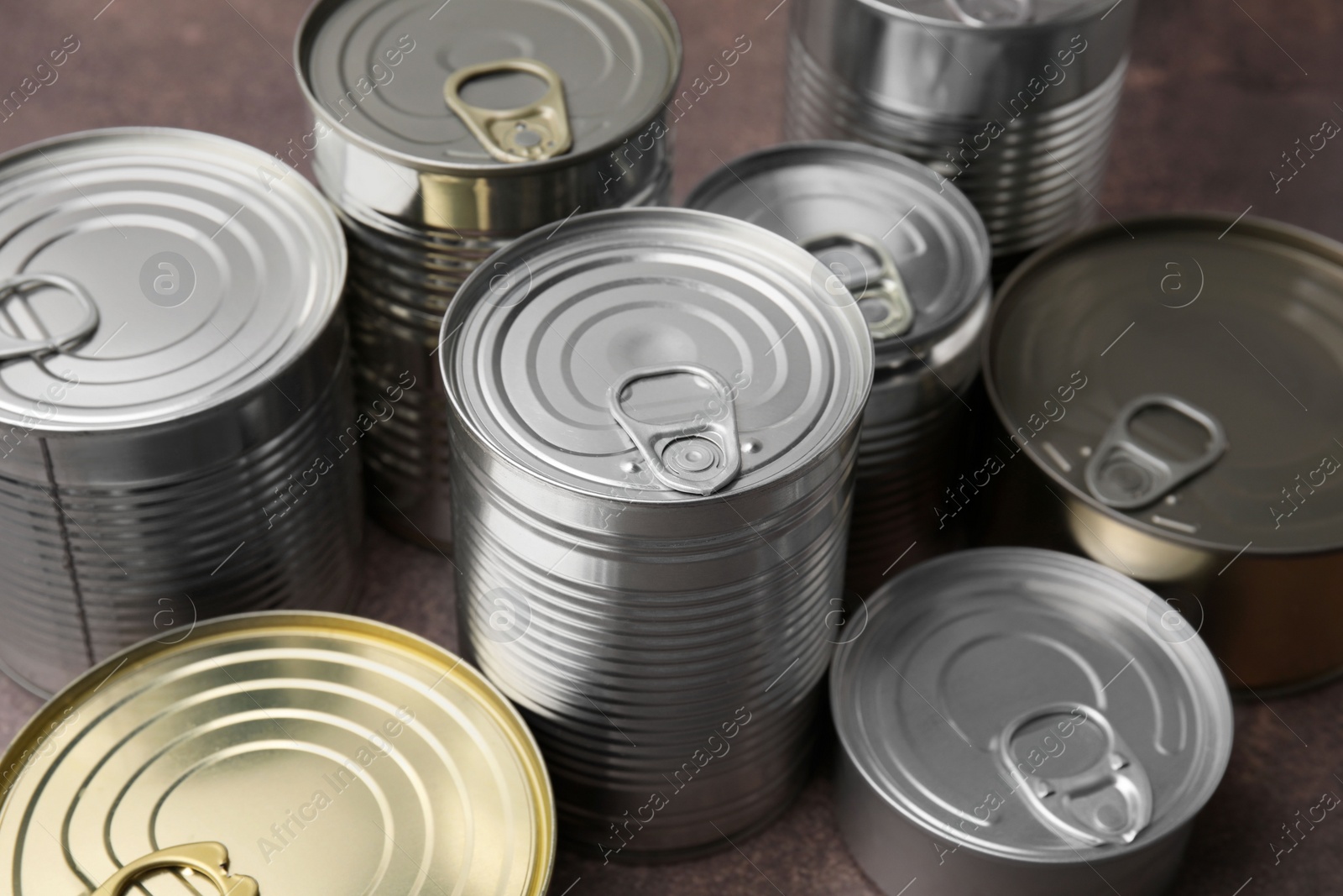 Photo of Many closed tin cans on brown table, closeup